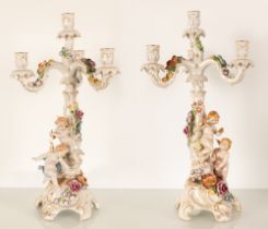Coppia di grandi candelieri in porcellana con decoro plastico formato da putti e ghirlande di fiori