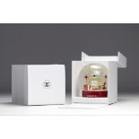 Chanel. Glass snow globe depicting a large bottle of NÂ°5 perfume, surrounded by gift packages adorn