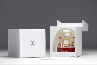 Chanel. Glass snow globe depicting a large bottle of NÂ°5 perfume, surrounded by gift packages adorn