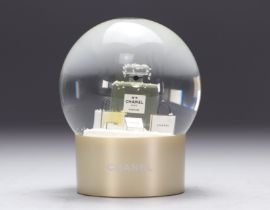 Chanel. Glass snow globe representing a bottle of NÂ°5 perfume surrounded by gift packages adorned w