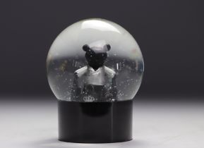 IKKS. Snow globe featuring a teddy bear wearing bags from a luxury brand.