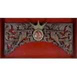 Wooden panel or ornament decorated with two cherubs mounted in a wooden frame on a red background