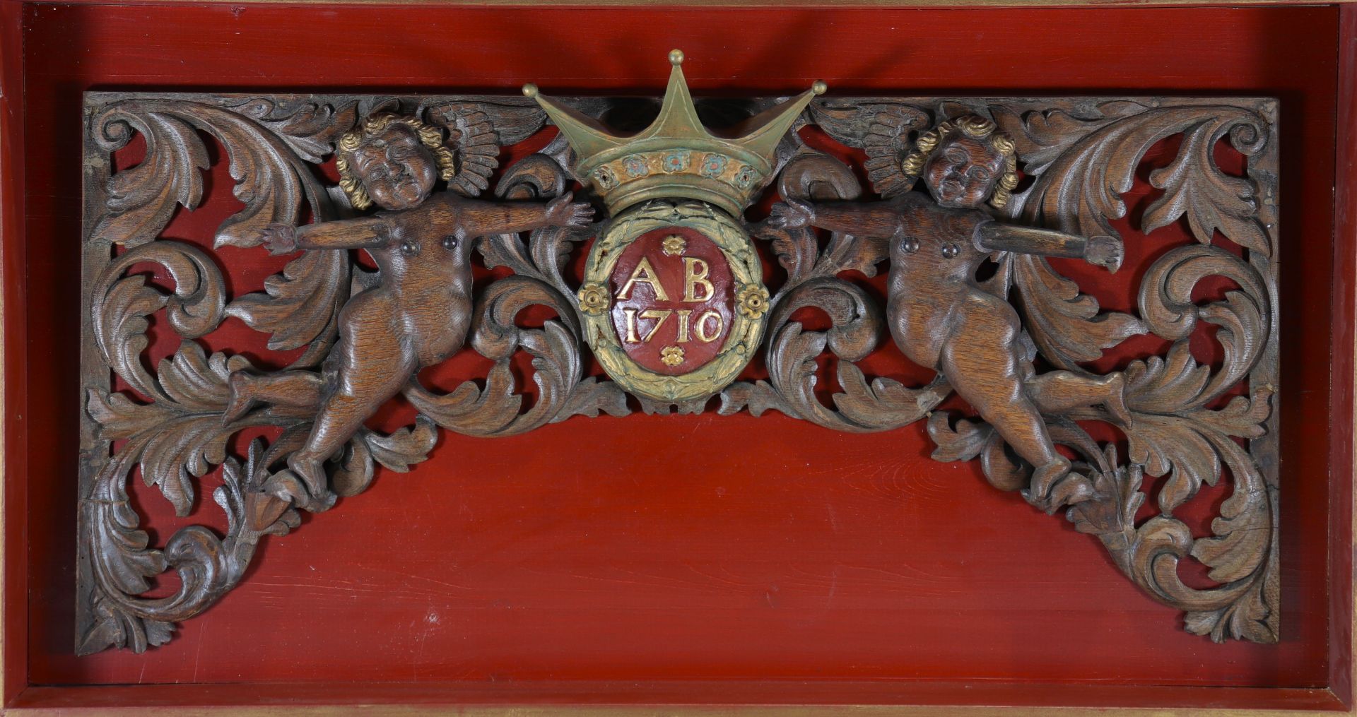 Wooden panel or ornament decorated with two cherubs mounted in a wooden frame on a red background