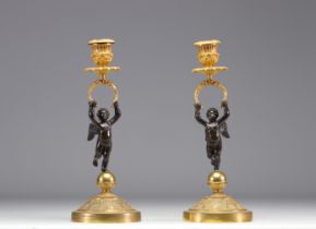 (2) Pair of candlesticks in bronze with two patinas, decorated with cherubs from the Empire period