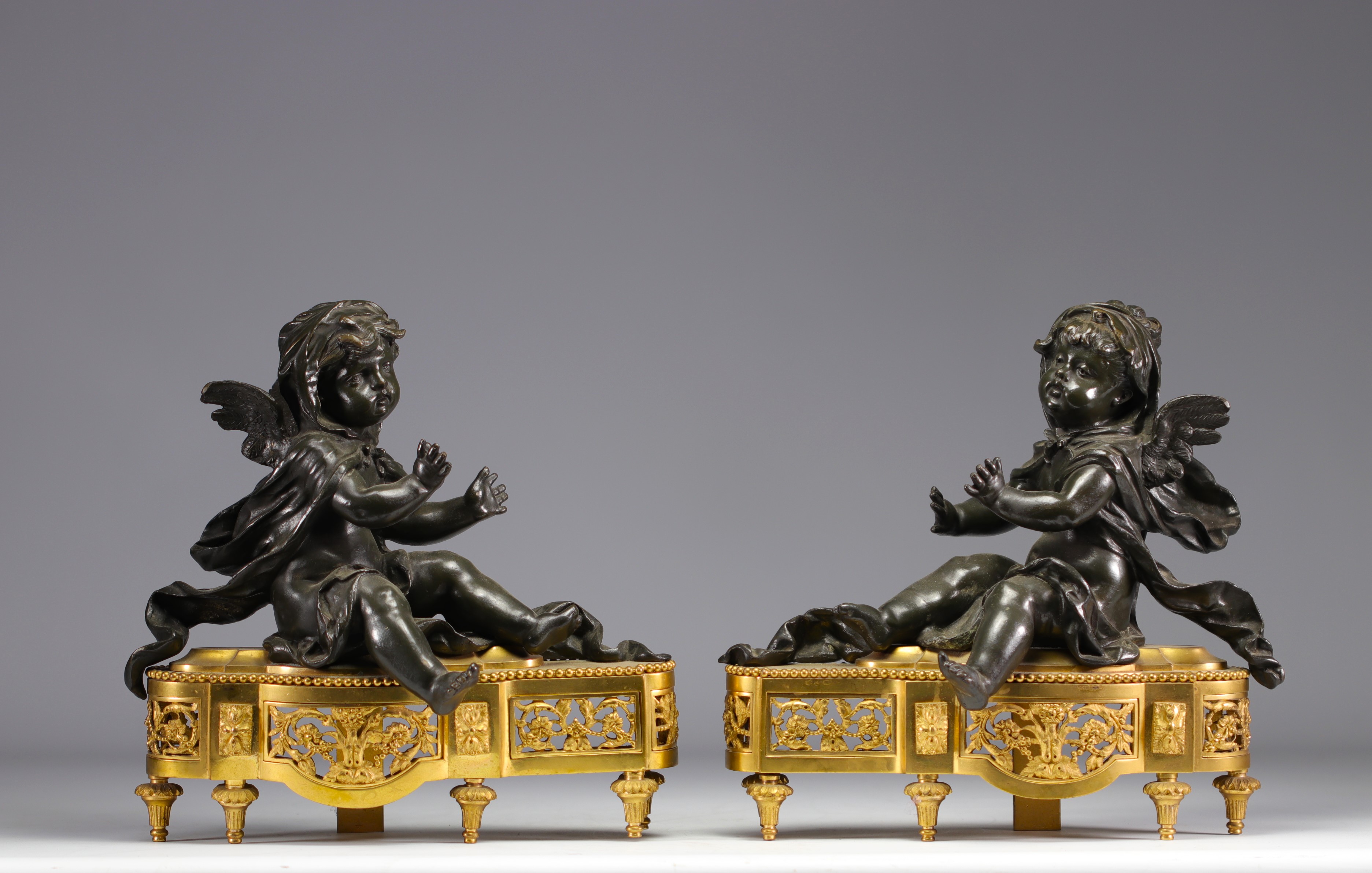 (2) Pair of Louis XV-style bronze andirons with brown patina and putti decoration on a gilded bronze