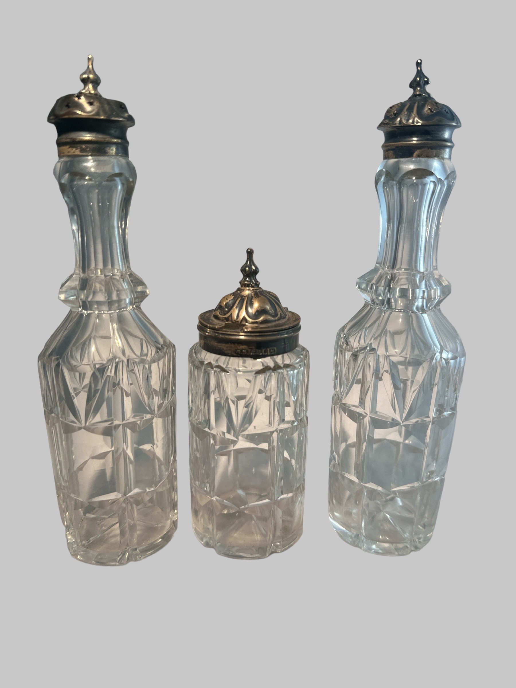 Three Victorian cut glass bottles with silver mounts, probably part of a cruet set. Birmingham