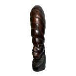 A standing African carved wooden sculpture in the shape of a woman’s head with a phallic design