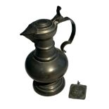 Pewter lidded jug (height 26cm) with two-sided religious token (possibly lead) 6cm x 5cm.