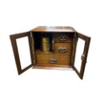 Smokers cabinet with two glazed doors, three internal drawers with brass drop handles, brass tobacco