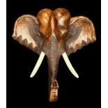 A large wooden wall mounted wooden Elephant head with white painted tusks. Height 100cm, Width