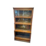 An oak four section Globe Wernicke sectional bookcase with lift up glass fronts, also plinth base