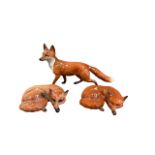 Beswick, a group of three Fox figurines, to include; larger prowling fox (length 22.5cm) and two