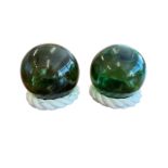 Pair of hand blown green glass fishing floats (buoys), each on rope stand.