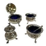 Two silver salts and a mustard pot with blue liners and spoons.