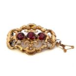 A 19th century brooch set with three garnets in a gilt open scroll surround.