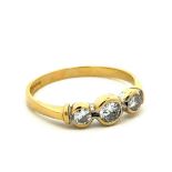 An 18ct gold and three stone diamond ring. Central diamond approx 0.25ct. Size R. Weight 2.92g.