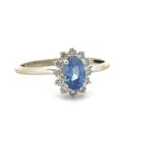 An 18ct white gold sapphire and diamond cluster ring. Sapphire 0.71ct and is cornflower blue.