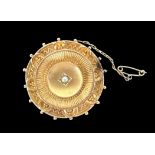 A late Victorian Estruscan-revival shield brooch with a pearl set to a raised central bosss.