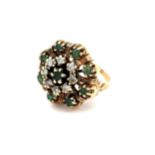 A gold dress ring stamped 14K set with emeralds and diamonds in a flower design. Size M.