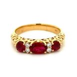 A three stone ruby ring with diamond accents, set in gold marked 18ct. Oval cut ruby to centre