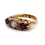 A three stone amethyst ring with seed pearls in a hallmarked 9ct gold scroll setting. Size K.