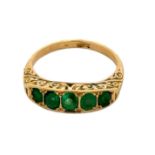 A five stone emerald ring with scroll gallery, stamped 18ct. Size O. Total weight 4.22g. Please