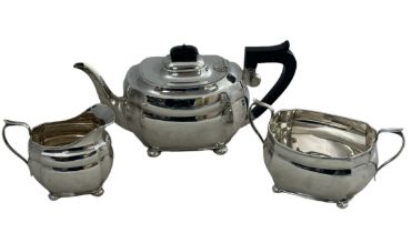 A George V silver teapot, cream jug and sugar bowl, in oblong form with canted corners and bun feet.