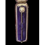 A cased diamond and pearl unmarked yellow metal pin. 63mm in length. Weight 2.17g. Please see the