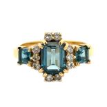 An 18ct gold and London blue topaz and diamond ring, size O. A central emerald cut topaz 8mm x 6mm