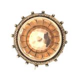 A Victorian yellow metal circular brooch with faceted central dome and glass panel to the reverse