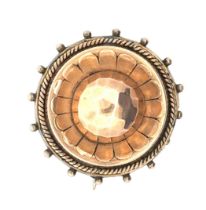 A Victorian yellow metal circular brooch with faceted central dome and glass panel to the reverse