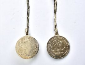 Two silver medallion pendant necklaces. One with a floral design one on one side and stamped 'SS'