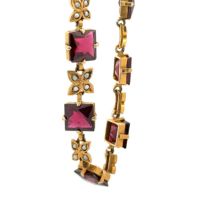 A yellow metal bracelet set with 10 square cut garnets interspersed with flower shaped links each