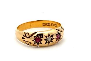 A hallmarked18ct three stone gypsy ring with scroll shoulders set with two rubies and a diamond,