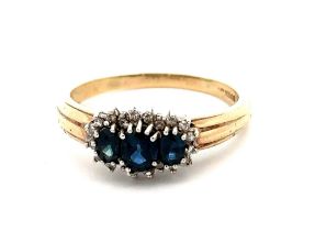 A three stone sapphire and diamond cluster ring, set in 9ct yellow gold. London hallmarks. Size S/T.