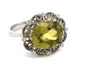 A sphene and diamond ring, size P/Q. The oval cut sphene of approx 14mm x 11mm is set in an