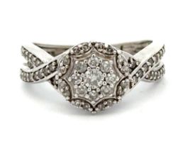 A 9ct white gold diamond cluster ring with a crossover split shank. London hallmarks. Size N. Weight