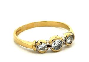 An 18ct gold and three stone diamond ring. Central diamond approx 0.25ct. Size R. Weight 2.92g.