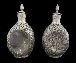 A pair of oriental Japanese overlaid white metal and glass decanters with stoppers. Each clear glass