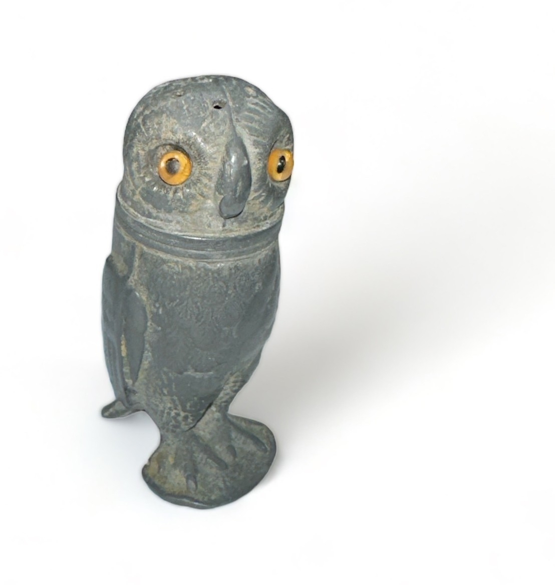 A late 19th / early 20th Century pewter novelty pepperette in the form of an owl, with glass eyes.