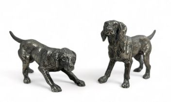 A pair of white metal dog figures of dogs, largest approx 17cm in length.