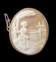 A gold shell cameo brooch depicting a lady looking over a fence to a house beyond. With rope twist