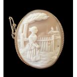 A gold shell cameo brooch depicting a lady looking over a fence to a house beyond. With rope twist
