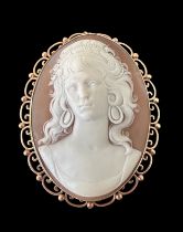 A large finely-carved shell cameo in 9ct gold filigree scroll surround which can be worn as a brooch