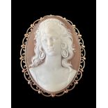 A large finely-carved shell cameo in 9ct gold filigree scroll surround which can be worn as a brooch