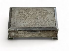 A small rectangular silver trinket box with engine turned design, on four feet with a wood lined