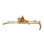 A 9ct gold bar brooch in the form of a riding crop with a gold and enamel horse and jockey. Set with