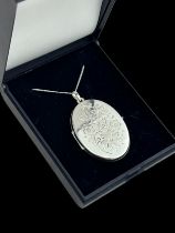 A silver locket with foliate design stamped 'Germany MM 925' on a white metal chain. Locket 4cm in