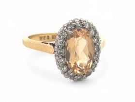 An oval imperial topaz and diamond cluster ring, stamped 18ct and PLAT, by maker W.E.G. Topaz approx