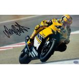 Framed signed Valentino Rossi picture. Rossi pictured cornering on his yellow Yamaha motorbike.